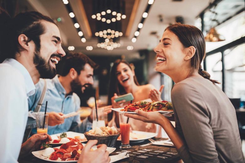 A group of people laughing and eating at a restaurant