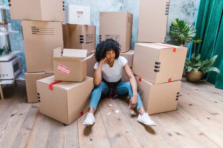 Young woman sitting on the floor, surrounded by boxes before international moving