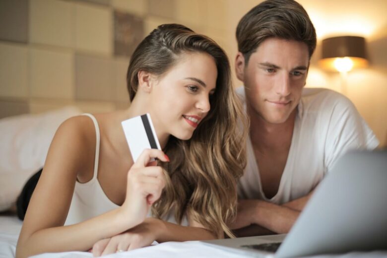 A woman holding a debit card and a man in front of a laptop