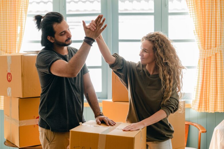 A man and a woman high-fiving behind a box