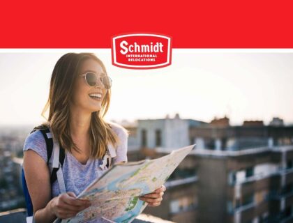 Woman smiling and holding a map Schmidt International Relocations Logo