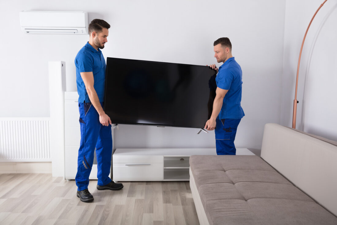 Two professional movers moving a TV