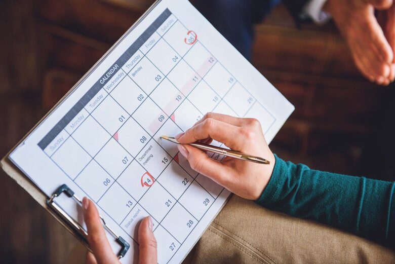 Close up of arms of woman holding schedule. She choosing certain date