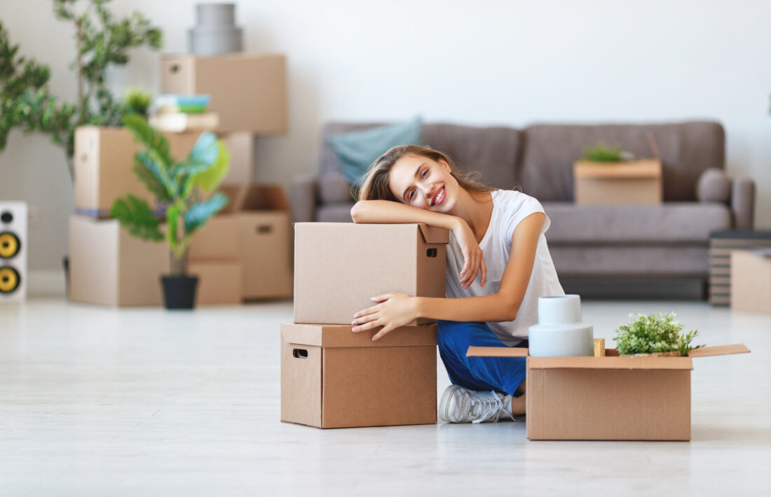 A smiling girl sitting with packed boxes