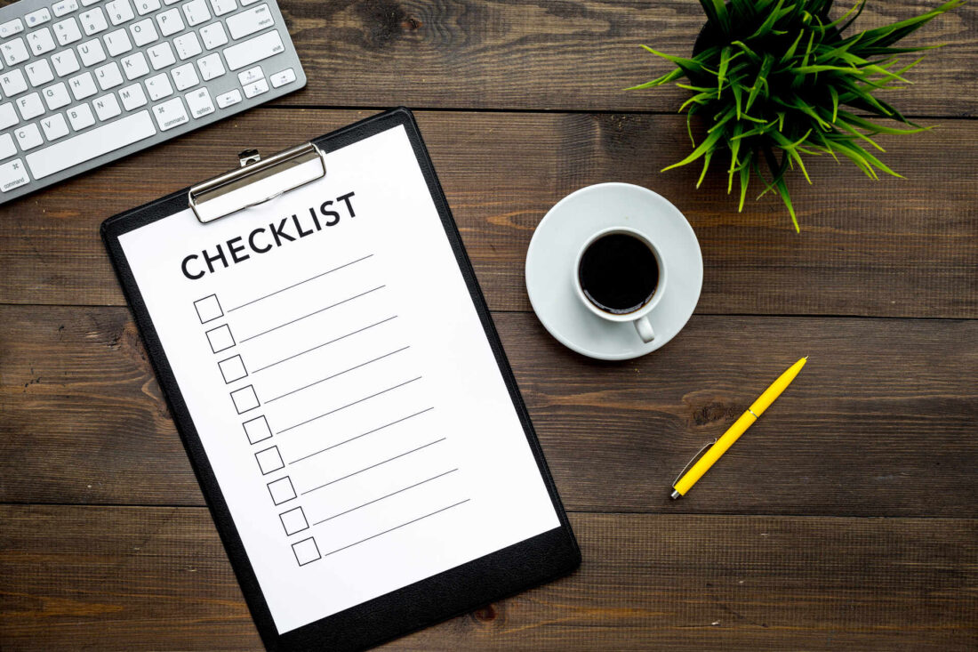 A checklist on the table with a pen and a cup of coffee