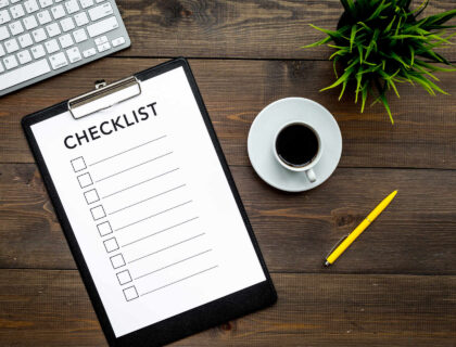 A checklist on the table with a pen and a cup of coffee