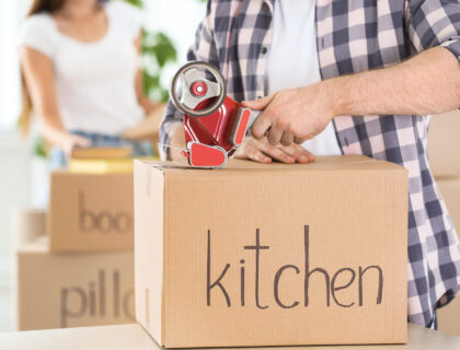 A man sealing a box with kitchen written on it