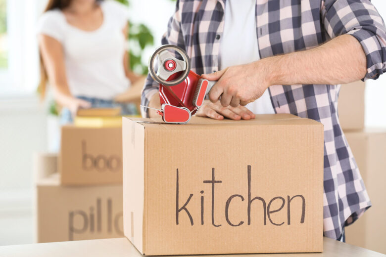 A man sealing a box with kitchen written on it