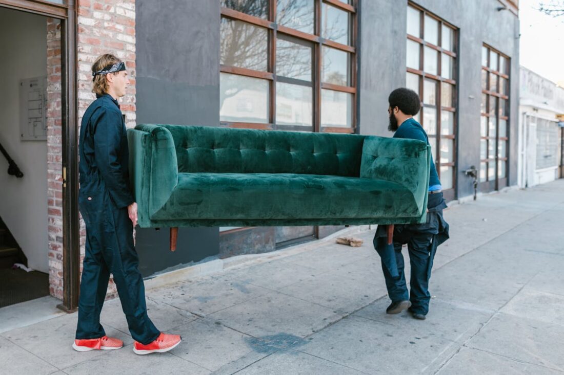 Two movers carrying a velvet sofa