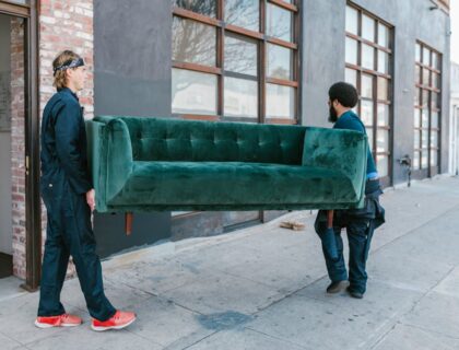 Two movers carrying a velvet sofa