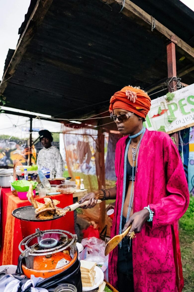 Vendor preparing traditional local street food at a lively outdoor night market in Kenya.